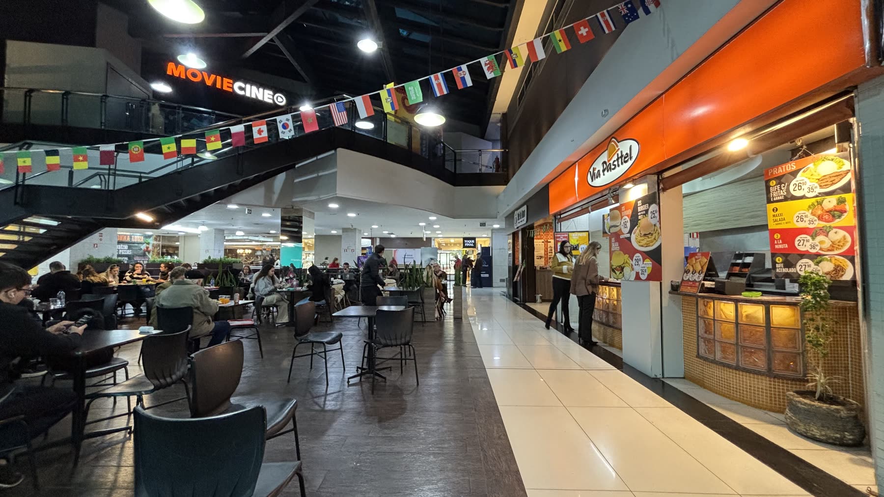Praça de alimentação do Lindóia Shopping com o letreiro do MovieCine ao fundo